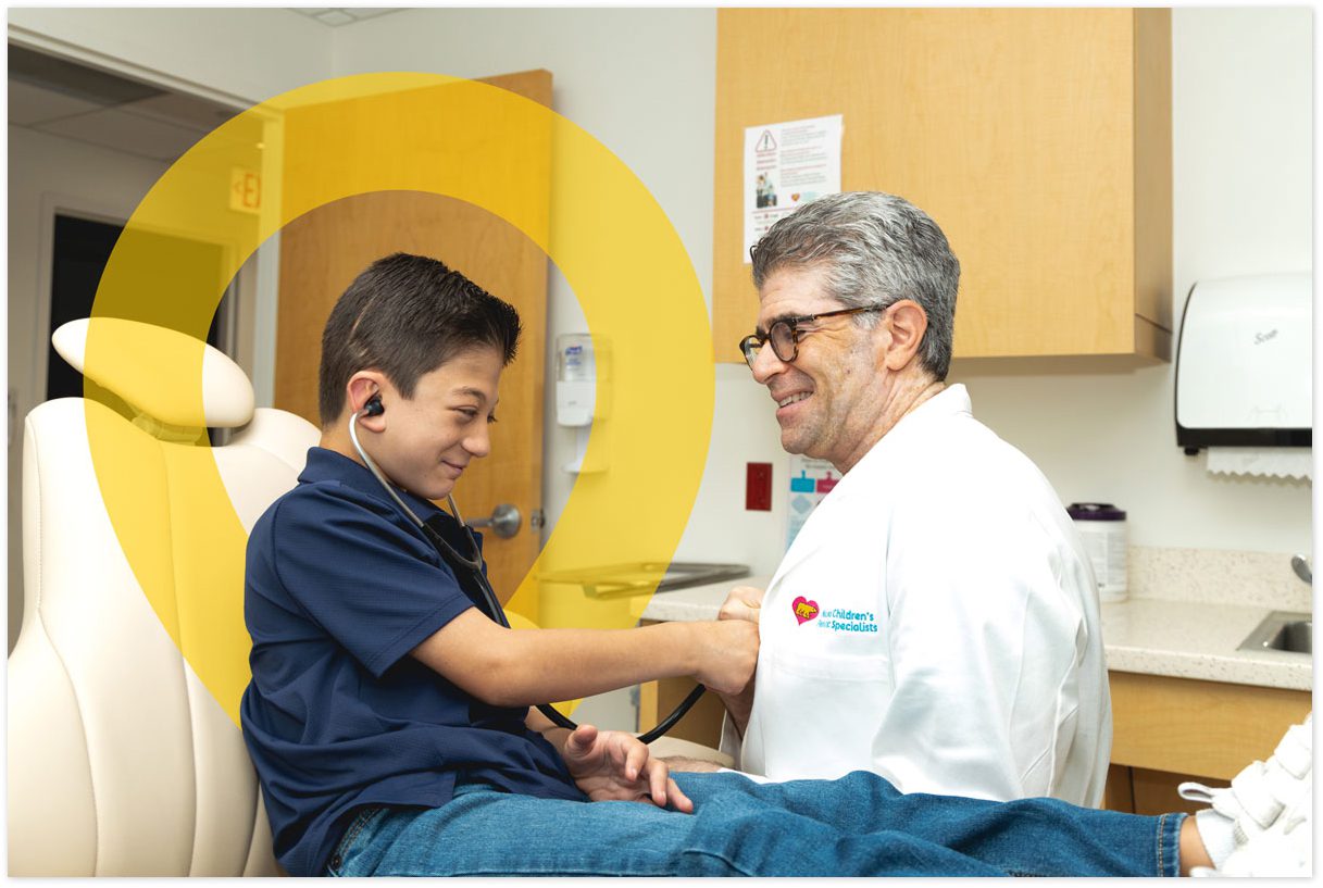Child using a stethoscope during a visit with a pediatric specialist.
