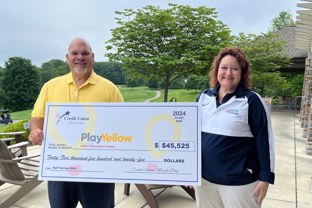 Two people holding a large Play Yellow donation check for $45,525 raised by Credit Union Miracle Day during a 2024 golf outing.