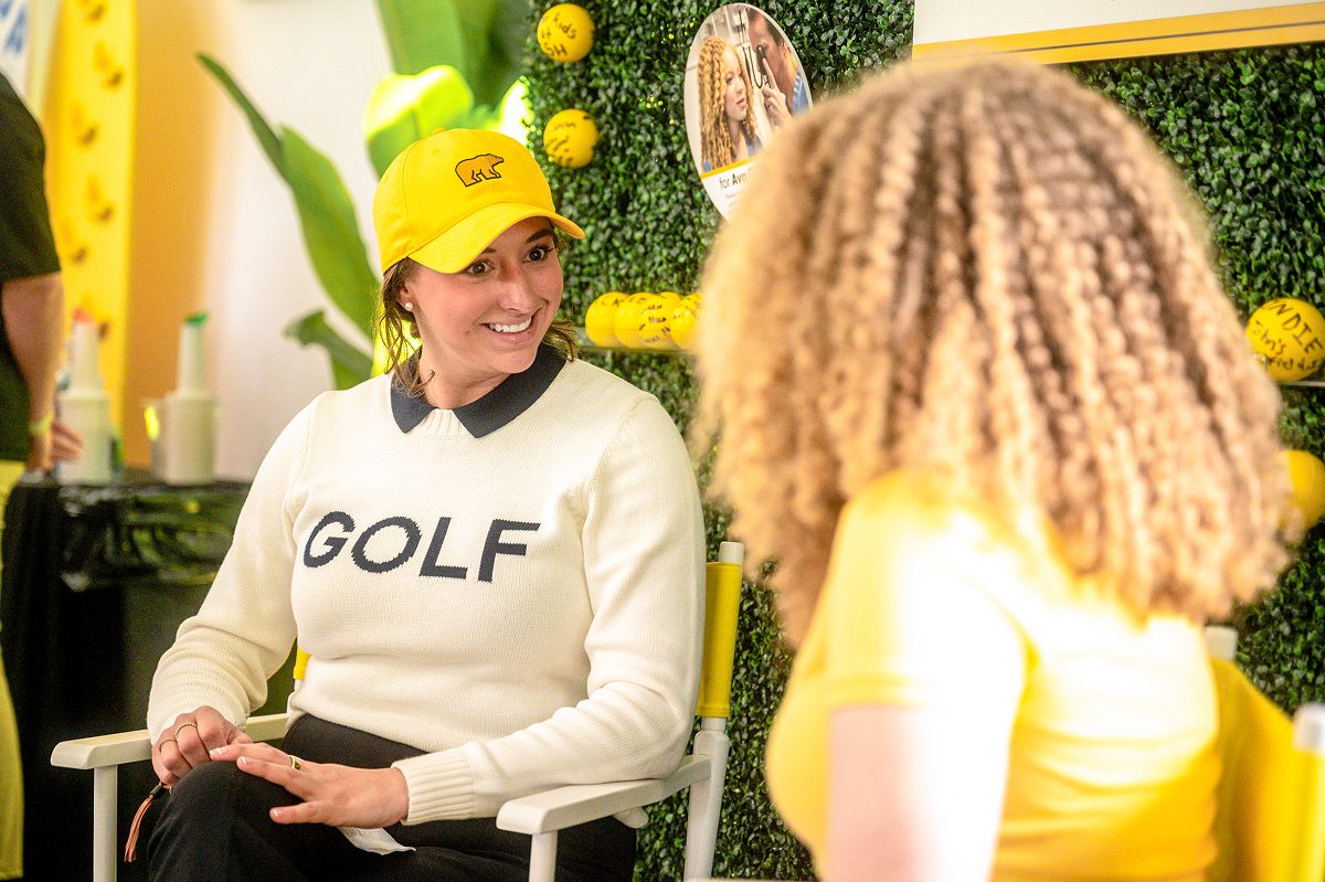 Alexa Pano speaking with a Play Yellow champion at an event display.