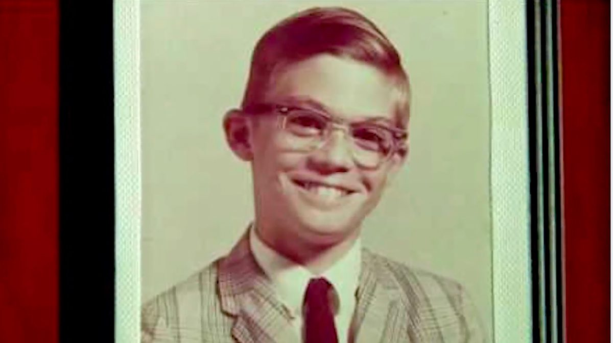 A vintage color photograph of a young boy with glasses and a buzz cut, wearing a plaid jacket and tie; this is Craig Smith, whose love of yellow inspired the Play Yellow movement.
