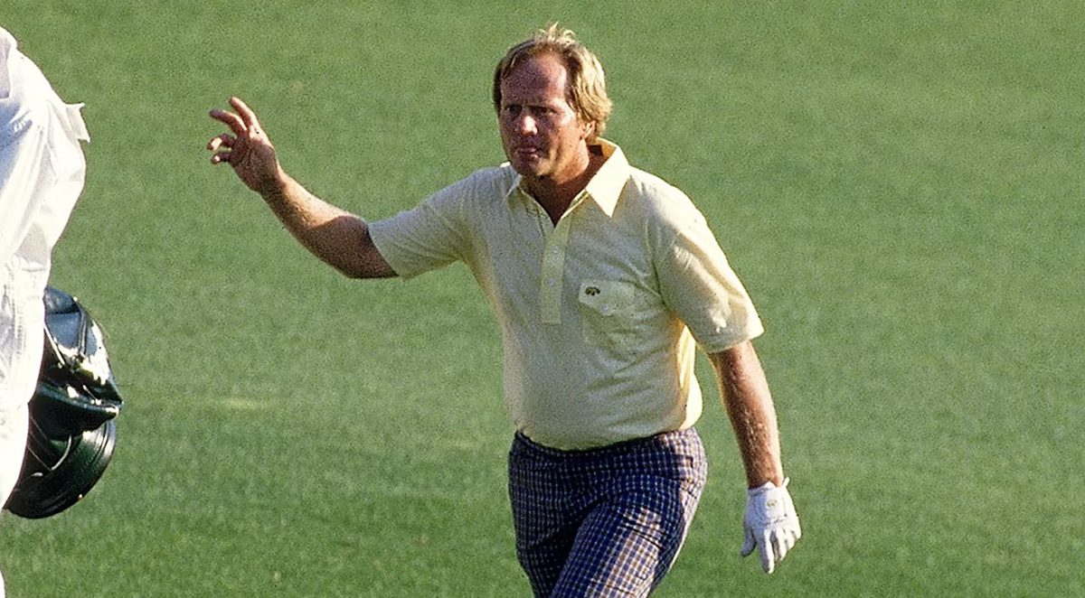 An action shot of Jack Nicklaus during his professional playing days, wearing a light yellow polo shirt and patterned blue trousers while gesturing on a green.